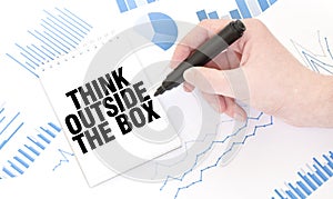 Businessman holding a black marker, notepad with text THINK OUTSIDE THE BOX, business concept