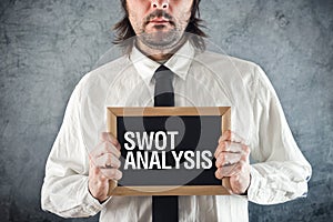 Businessman holding blackboard with SWOT ANALYSIS title