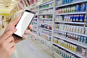 Businessman holding blank screen for text on smartphone, mobile, cell phone with blurry cosmetics shelf background