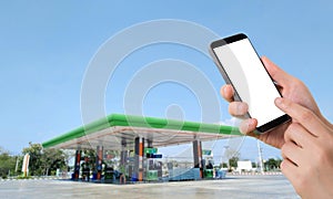 Businessman holding blank screen for text on smartphone, mobile, cell phone with blurry oil station