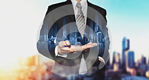 Businessman holding blue modern buildings hologram on hand, with black and white city background photo