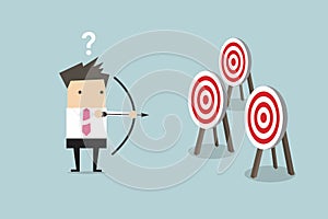 Businessman holding bow and arrow confused by multiple bulls eye target