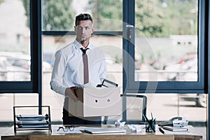 Businessman holding box while standing near workplace