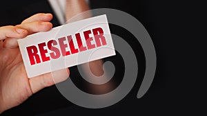 Businessman holding a card with Reseller word. Reselling business concept