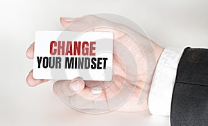 businessman holding a card with text CHANGE YOUR MINDSET