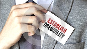 Businessman holding a card with text ESTABLISH CREDIBILITY photo