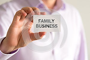 Businessman holding card with text FAMILY BUSINESS