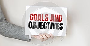 Businessman holding a card with text GOALS AND OBJECTIVES
