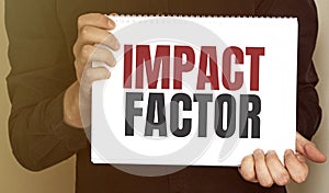 Businessman holding a card with text IMPACT FACTOR