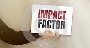 Businessman holding a card with text IMPACT FACTOR