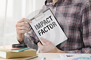Holding a card with text IMPACT FACTOR