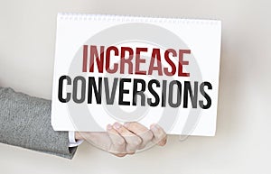 businessman holding a card with text INCREASE CONVERSIONS