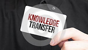 Businessman holding a card with text KNOWLEDGE TRANSFER,business concept