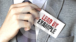 Businessman holding a card with text Lead by example