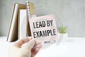 holding a card with text LEAD BY EXAMPLE