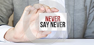Businessman holding a card with text NEVER SAY NEVER