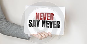 Businessman holding a card with text NEVER SAY NEVER