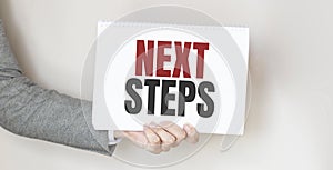 Businessman holding a card with text NEXT STEPS