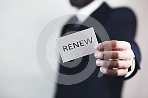 Businessman holding a card with text renew