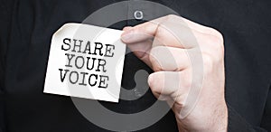 Businessman holding a card with text SHARE YOUR VOICE,business concept