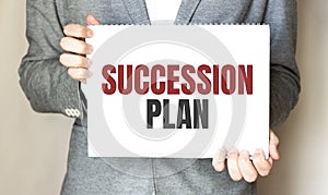 Businessman holding a card with text SUCCESSION PLAN