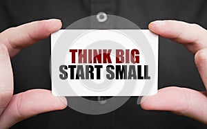 Businessman holding a card with text THINK BIG START SMALL, business concept