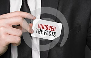 Businessman holding a card with text UNCOVER THE FACT