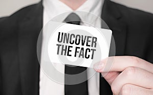 Businessman holding a card with text UNCOVER THE FACT