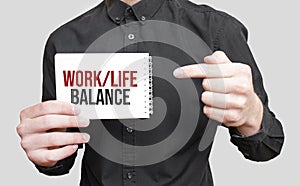 Businessman holding a card with text work life balance,business concept