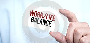 Businessman holding a card with text work life balance,business concept