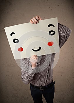 Businessman holding a cardboard with a smiley face on it