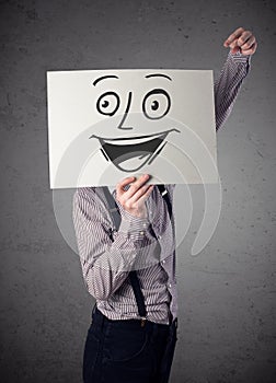 Businessman holding a cardboard with smiley face on it in front