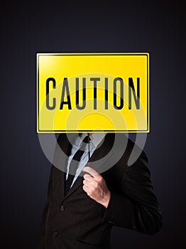 Businessman holding a caution sign