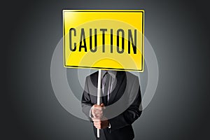 Businessman holding a caution sign