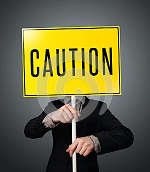 Businessman holding a caution sign