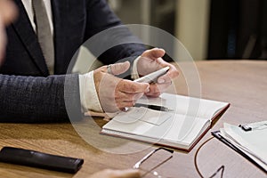 Businessman holding a cell phone and writing sms message in office,businessman use mobile smart phone,Close up of a man using mob