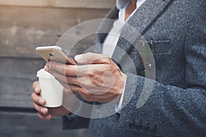 Businessman holding coffee and reading phone