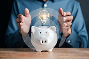 Businessman holding coin into piggy bank with light bulb icon. saving money idea strategy and financial, investment, bank, finance