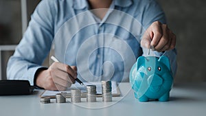 A businessman holding a coin in a piggy bank. Placing coins in a row from low to high is comparable to saving money to grow more.