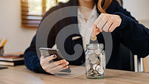 Businessman holding coins putting in glass with using smartphone and calculator to calculate concept saving money for finance