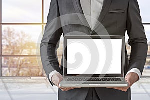 Businessman holding a computer and displaying the screen in the office