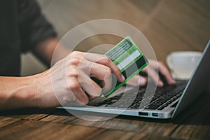 Businessman holding credit card and typing on laptop for online shopping and payment makes a purchase on the Internet, Online