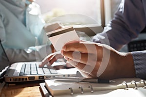 Businessman holding credit card and using laptop. Making payment while online shopping. E-commerce and modern technology concept