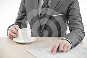 Businessman holding a cup of coffee and reading a newspaper