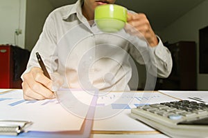 Businessman holding cup of coffee working meeting point to discuss the graph up and down of economy and work on desk