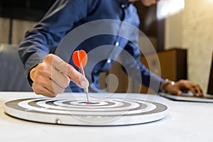 Businessman holding a darts aiming at the target center