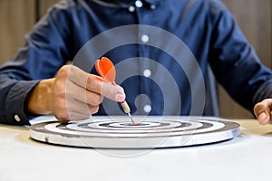 Businessman holding a darts aiming at the target center