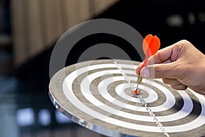 Businessman holding a darts aiming at the target center