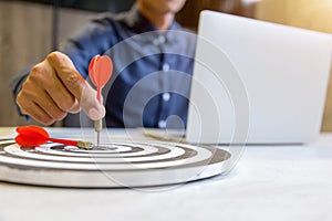 Businessman holding a darts aiming at the target center