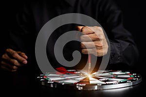 Businessman holding a darts aiming at the target center business goal concept